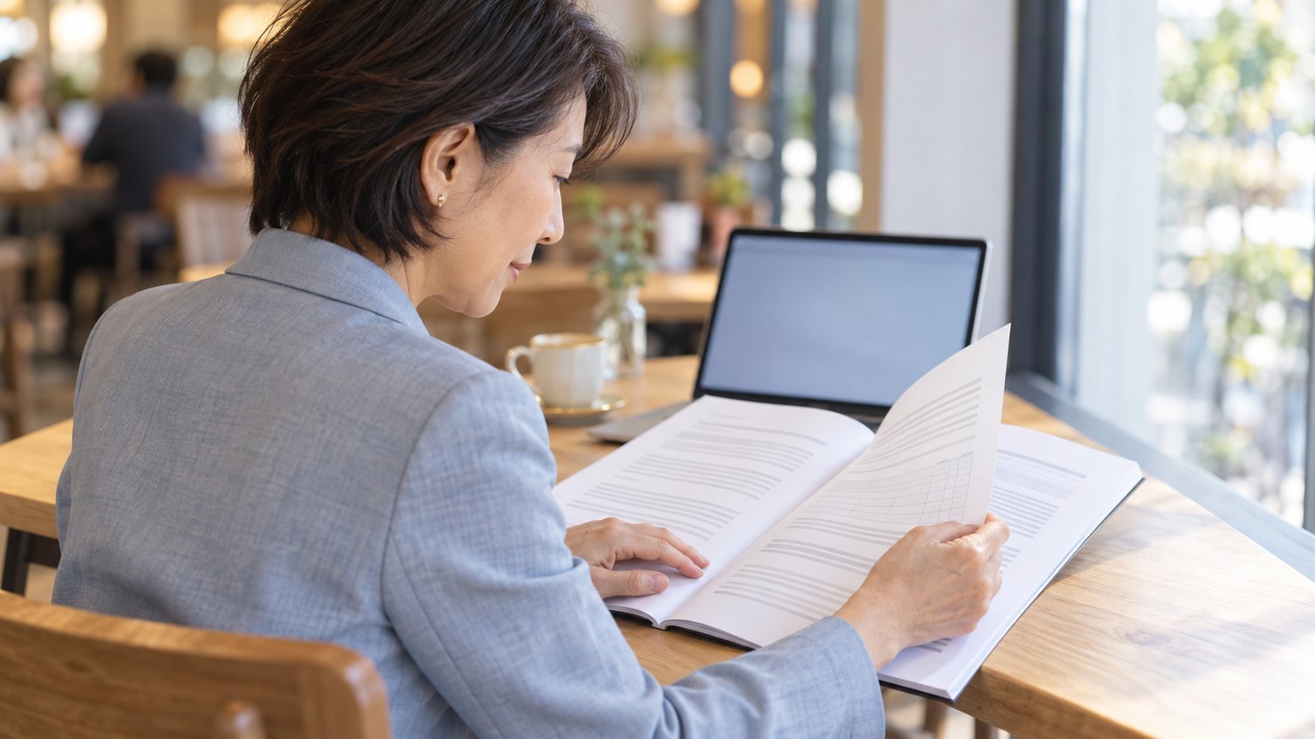 カフェで綴じた報告書を読む女性の横顔